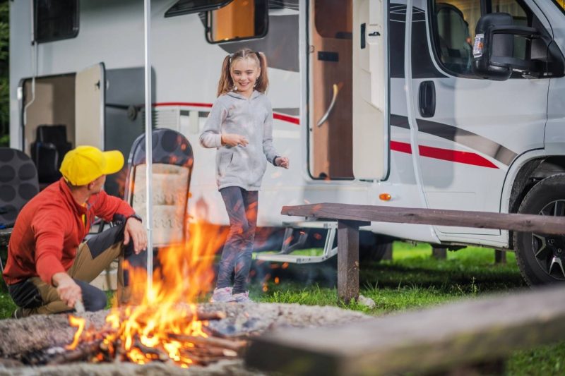 daughter and father outside of rv by campfire