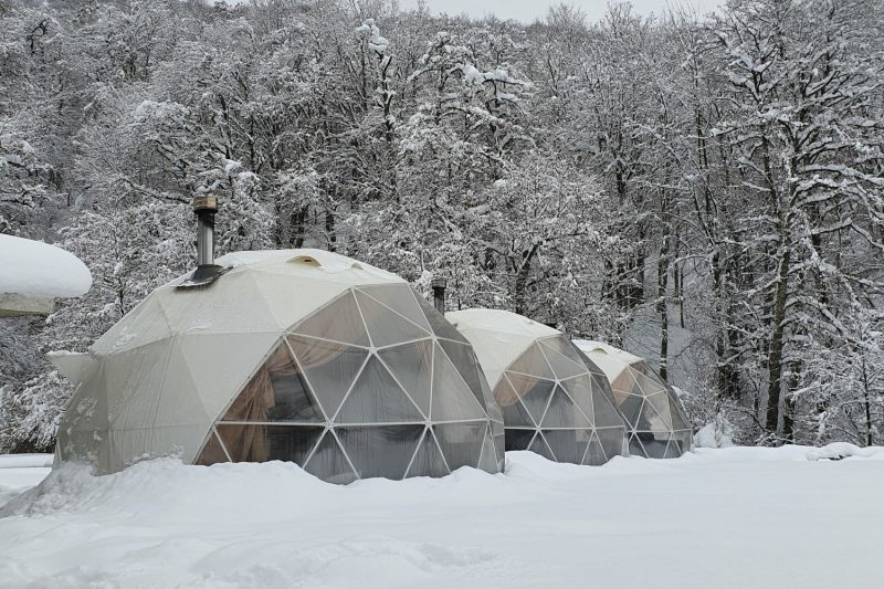 three glamping geodomes in winter landscape